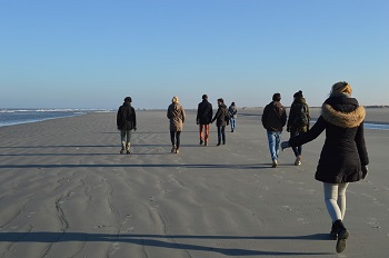 Foto van een groepje mensen dat over het strand wandelt.